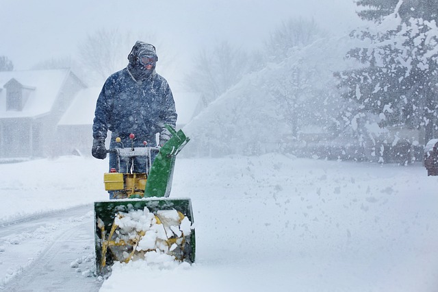man pushing snowblower in snow